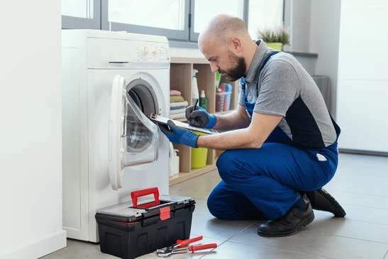 Une personne utilise un tournevis pour installer ou réparer un four micro-ondes blanc encastré dans une cuisine moderne