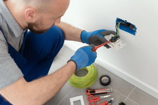 Électricien professionnel effectuant des mesures électriques dans un intérieur résidentiel